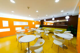 Cafetería dentro de una fábrica. Las paredes son de colores brillantes y el lugar es muy luminoso.