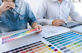 Dos hombres mirando las paletas de colores. Hay un plano del arquitecto sobre la mesa.